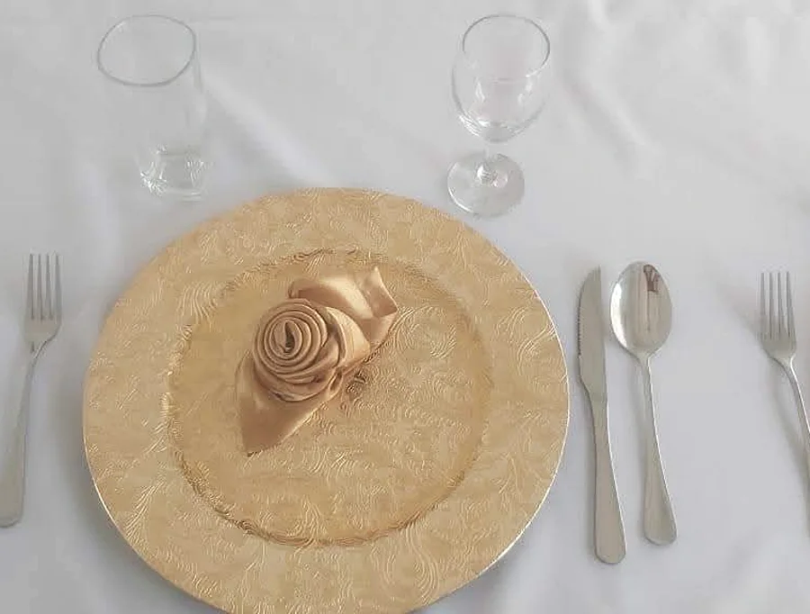 Lugar individual con plato dorado, cubiertos y cristalería