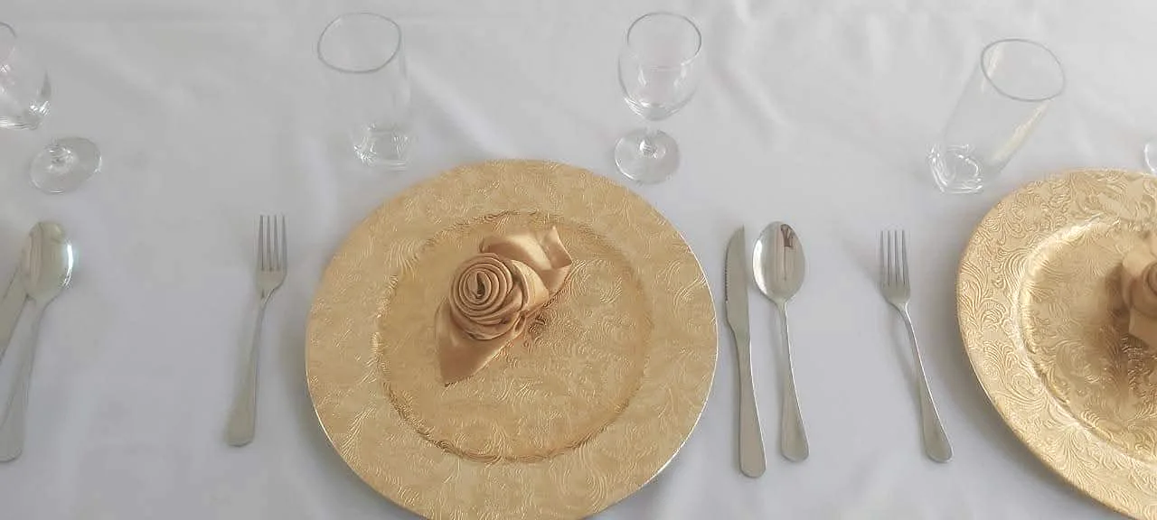 Detalle de una base dorada con servilleta en forma de rosa